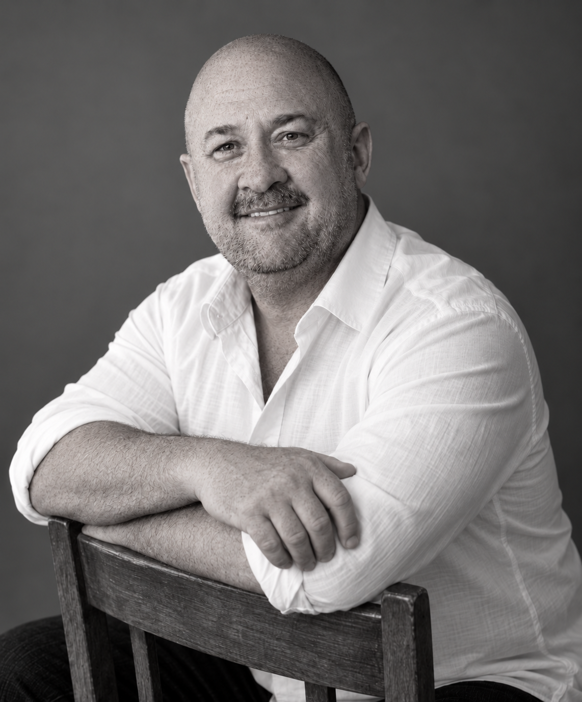 Wade Sisco seated with his arms resting on a chair back